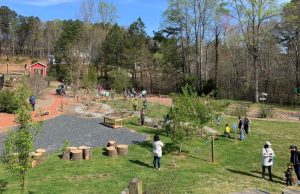 The earthen mound’s summit offers a vantage point over the Orchard’s playground elements and fruit trees.