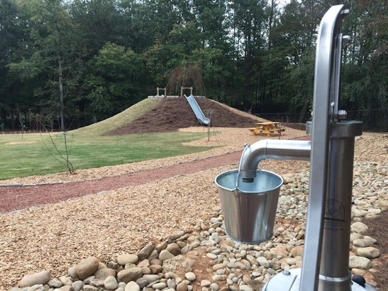 A hand water pump provides hands-on engagement and sensory exploration.